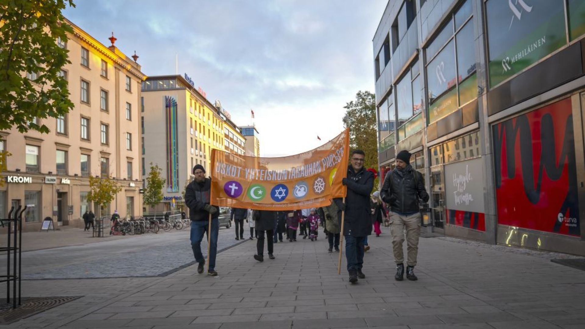 Kuvassa USKOT-banderolli ja rauhankävelyn osallistujia Turussa.